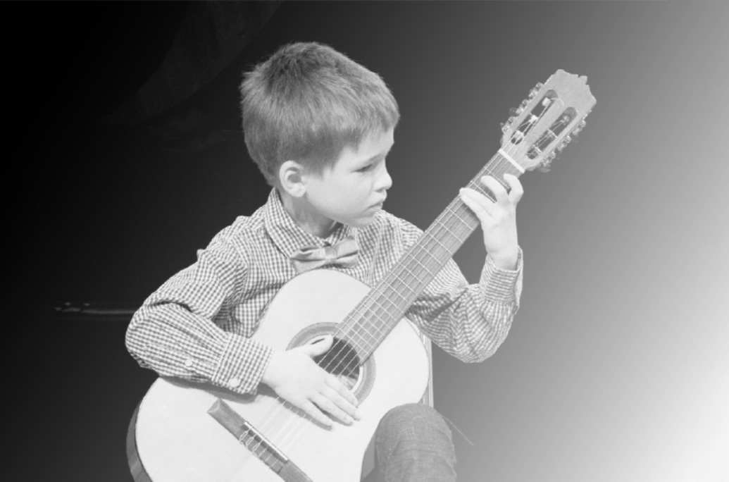 Černobílé foto žáka s kytarou